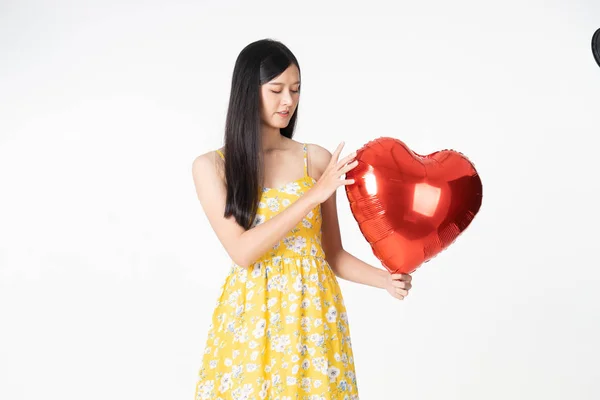 Mujer joven asiática en vestido amarillo sostiene el corazón globo rojo. Joven —  Fotos de Stock