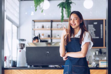Kafeteryada kollarını kollar halinde duran genç asyalı garson. C