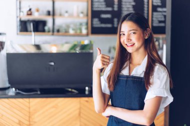 Kafeteryada kollarını kollar halinde duran genç asyalı garson. C
