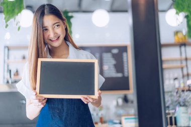 Kafeteryada kollarını kollar halinde duran genç asyalı garson. C