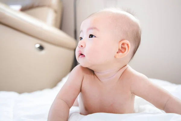 Aziatische baby blij in de kamer. Aziatische baby meisje liggend op bed . Stockfoto