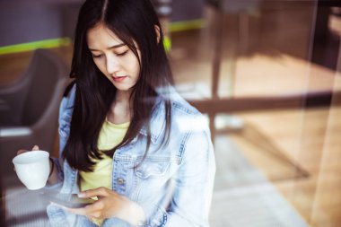 Güzel bir gülümseme ile Asyalı kadın dinlenme sırasında cep telefonu tutun i