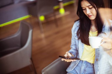 Güzel bir gülümseme ile Asyalı kadın dinlenme sırasında cep telefonu tutun i