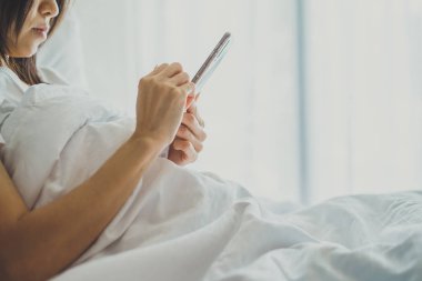 Cep telefonu ile yatakta yatak odasında Asya kız. Closeup 