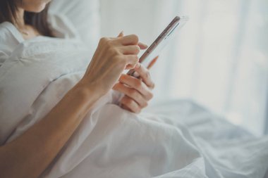 Cep telefonu ile yatakta yatak odasında Asya kız. Closeup 