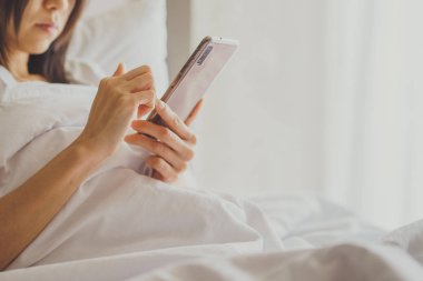 Cep telefonu ile yatakta yatak odasında Asya kız. Closeup 