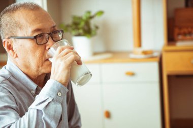 yaşlılık, sağlık sorunu, görme ve insan kavramı - kanepede oturan ve evde baş ağrısı olan Asyalı yaşlı adam yakın.o Baş Ağrısı Belirtileri olabilir.She ağrılı ve hasta görünüyor