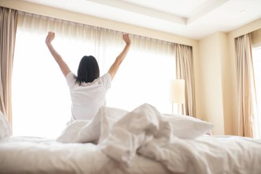 Uyanmak sonra yatakta uzanan kadın, arka görünüm. Kadın sittin