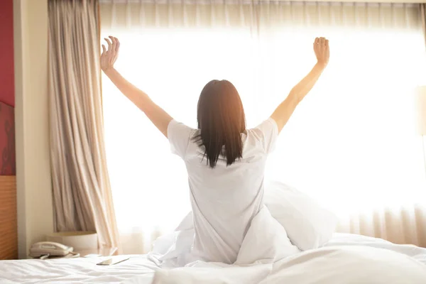 Woman stretching in bed after waking up, back view. Woman sittin — Stock Photo, Image
