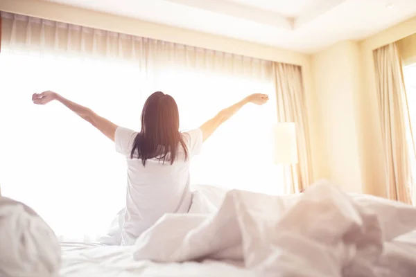 Mulher esticada na cama depois de acordar, vista para trás. Mulher sentada — Fotografia de Stock