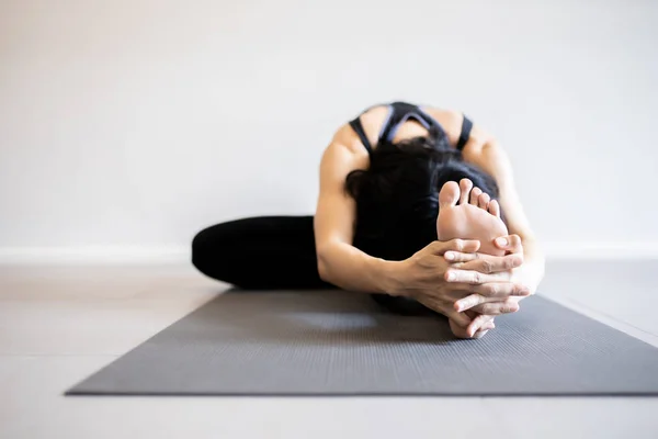 Junge Frau praktiziert Yoga im grauen Hintergrund. — Stockfoto