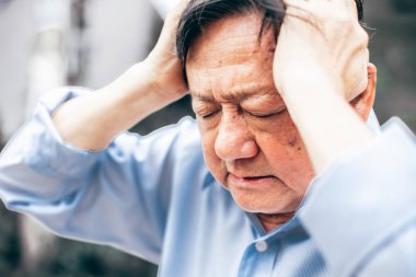 Baş ağrısı olan yaşlı bir adamın portresi.