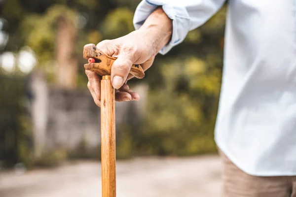 Close up of elderly hands in wrinkles holding walking stick.elde