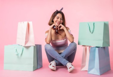 Asya güzel genç kadın pembe pastel arka plan üzerinde yürüyüş. Gülümsüyor ve alışveriş poşetlerini tutuyordu. o güzel görünümlü güzel çekici parlaklık .