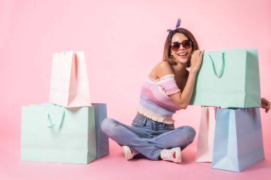 Asya güzel genç kadın pembe pastel arka plan üzerinde yürüyüş. Gülümsüyor ve alışveriş poşetlerini tutuyordu. o güzel görünümlü güzel çekici parlaklık .