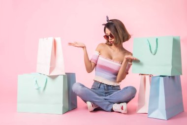 Asya güzel genç kadın pembe pastel arka plan üzerinde yürüyüş. Gülümsüyor ve alışveriş poşetlerini tutuyordu. o güzel görünümlü güzel çekici parlaklık .