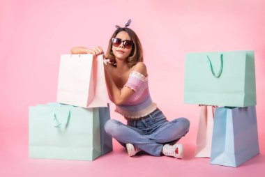 Asya güzel genç kadın pembe pastel arka plan üzerinde yürüyüş. Gülümsüyor ve alışveriş poşetlerini tutuyordu. o güzel görünümlü güzel çekici parlaklık .