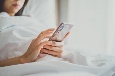 Cep telefonu ile yatakta yatak odasında Asya kız. Closeup 