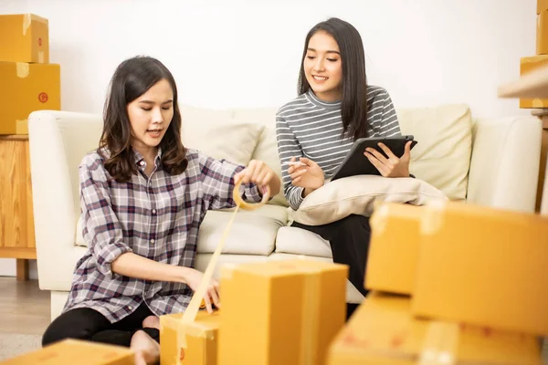 Worker In Warehouse Checking Boxes Using Digital Tablet.Start up small business entrepreneur SME or freelance man and woman working  at home concept, Young Asian small business owner,online marketing.