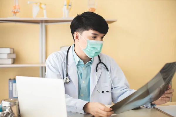 Asian young Doctor consulting patient over the phone.man with headphone isolated in clinic.Portrait of happy smiling young doctor in headset.