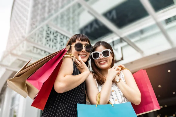 Asain woman in shopping. Happy woman with shopping bags enjoying in shopping.lifestyle concept.Smiling girl  holding colour paper bag.Friends walking in shopping mall