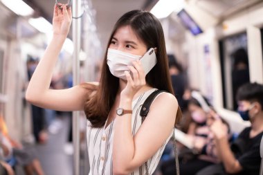 Genç Asyalı iş kadını öksürük ve ağzı örtüyor, virüslerden korunmak için tıbbi maske takıyor. İnsanlar COVID-19 virüslerinden uzak duruyor. Enfeksiyon riskine karşı sosyal mesafe..