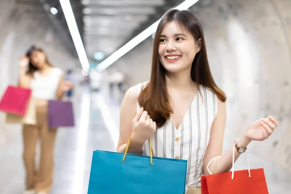 Asain woman in shopping. Happy woman with shopping bags enjoying in shopping.lifestyle concept.Smiling girl  holding colour paper bag.Friends walking in shopping mall.