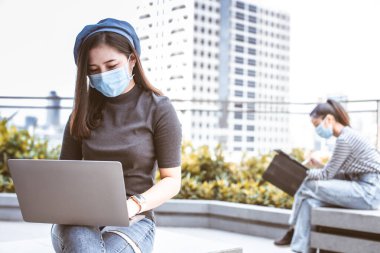 Asyalı kadın serbest çalışıyor. Koroner arter enfeksiyonunu önlemek için evde otururken maske takar (Covid-19). Karantinadan sonra toplanan kız arkadaşlar covid pandemic19 'un neden olduğu.