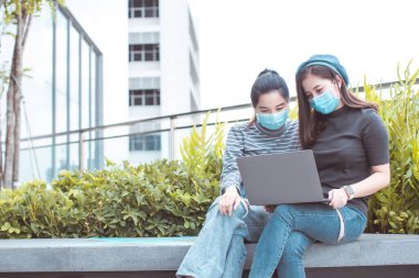 Asyalı kadın serbest çalışıyor. Koroner arter enfeksiyonunu önlemek için evde otururken maske takar (Covid-19). Karantinadan sonra toplanan kız arkadaşlar covid pandemic19 'un neden olduğu.