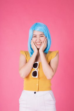 Renkli alışveriş torbalarıyla oldukça heyecanlı Asyalı bir kızın portresi pembe arka planda soyutlanmış görünüyor. Satış konsepti için renkli alışverişçi kadın. Genç mavi saçlı kız. .