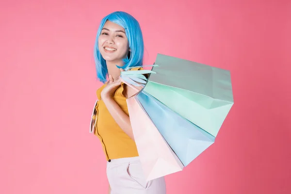 一个非常兴奋的亚洲女孩的画像 她带着五颜六色的购物袋 在粉色的背景下显得孤立无援 亚洲的购物狂女人带着五颜六色的购物袋进行夏季销售 — 图库照片