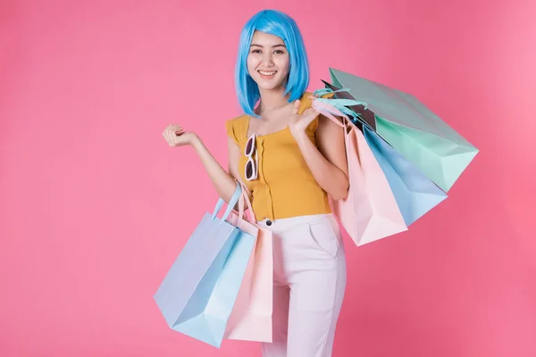 一个非常兴奋的亚洲女孩的画像 她带着五颜六色的购物袋 在粉色的背景下显得孤立无援 亚洲的购物狂女人带着五颜六色的购物袋进行夏季销售 — 图库照片
