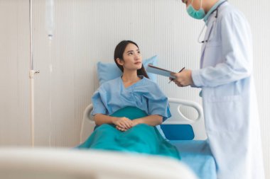 Tıp ve sağlık hizmetleri kavramı. Asyalı doktor hasta kadını hastaneye götürüyor. Doktor ya da hemşire koruma maskesi takıyor. Enfeksiyonu kontrol ediyor. .