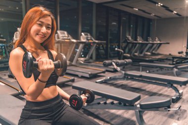 Güzel vücutlu, kaslı, genç Asyalı kadın halterle egzersiz yapıyor. Sportif kız spor salonunda ağırlık kaldırıyor..