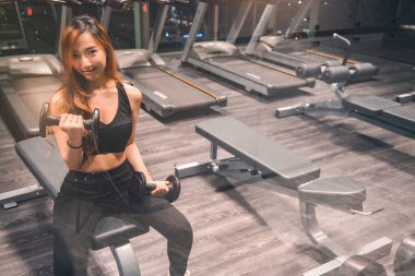 Güzel vücutlu, kaslı, genç Asyalı kadın halterle egzersiz yapıyor. Sportif kız spor salonunda ağırlık kaldırıyor..