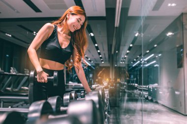 Güzel vücutlu, kaslı, genç Asyalı kadın halterle egzersiz yapıyor. Sportif kız spor salonunda ağırlık kaldırıyor..
