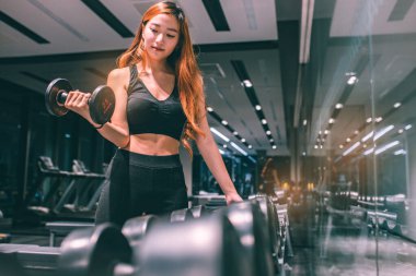 Güzel vücutlu, kaslı, genç Asyalı kadın halterle egzersiz yapıyor. Sportif kız spor salonunda ağırlık kaldırıyor..