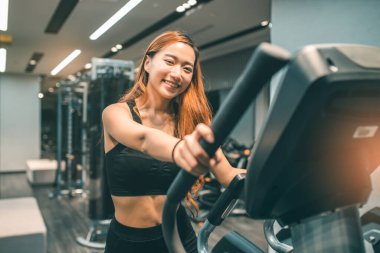 Egzersiz yapan kaslı Asyalı genç bir kadın. Sportif kız spor salonunda ağırlık kaldırıyor..
