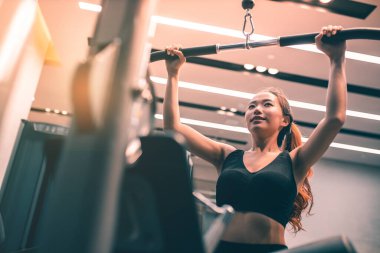 Egzersiz yapan kaslı Asyalı genç bir kadın. Sportif kız spor salonunda ağırlık kaldırıyor..