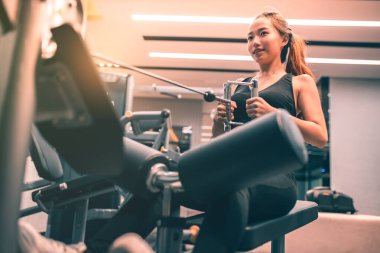 Egzersiz yapan kaslı Asyalı genç bir kadın. Sportif kız spor salonunda ağırlık kaldırıyor..
