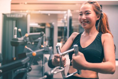 Egzersiz yapan kaslı Asyalı genç bir kadın. Sportif kız spor salonunda ağırlık kaldırıyor..