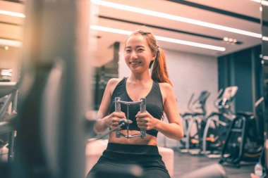 Egzersiz yapan kaslı Asyalı genç bir kadın. Sportif kız spor salonunda ağırlık kaldırıyor..
