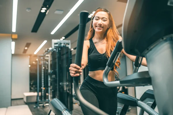 Egzersiz yapan kaslı Asyalı genç bir kadın. Sportif kız spor salonunda ağırlık kaldırıyor..