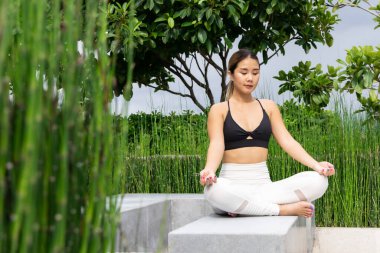 Bahçede yoga yapan genç bir kadının portresi. Kadın mutluluğu. Geçmişi bulanık. Sağlıklı yaşam tarzı ve rahatlama kavramı. Parkta yoga yapan genç Asyalı kız..