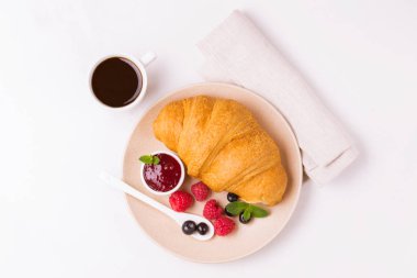 Bir fincan sıcak kahve, reçel ve meyveler kahvaltıda taze kruvasan. Seçici odak