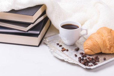 Bir fincan sıcak kahve, kruvasan, ekose ve kitap masada. Eğitim kavramı. Seçici odak