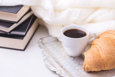 Bir fincan sıcak kahve, kruvasan, ekose ve kitap masada. Eğitim kavramı. Seçici odak