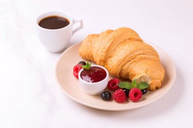 Bir fincan sıcak kahve, reçel ve meyveler kahvaltıda taze kruvasan. Seçici odak