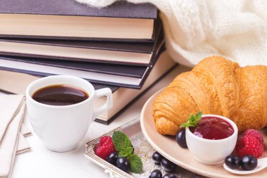 Bir fincan sıcak kahve, kruvasan, ekose ve kitap masada. Eğitim kavramı. Seçici odak