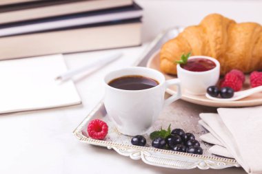 Bir fincan sıcak kahve, kruvasan, ekose ve kitap masada. Eğitim kavramı. Seçici odak